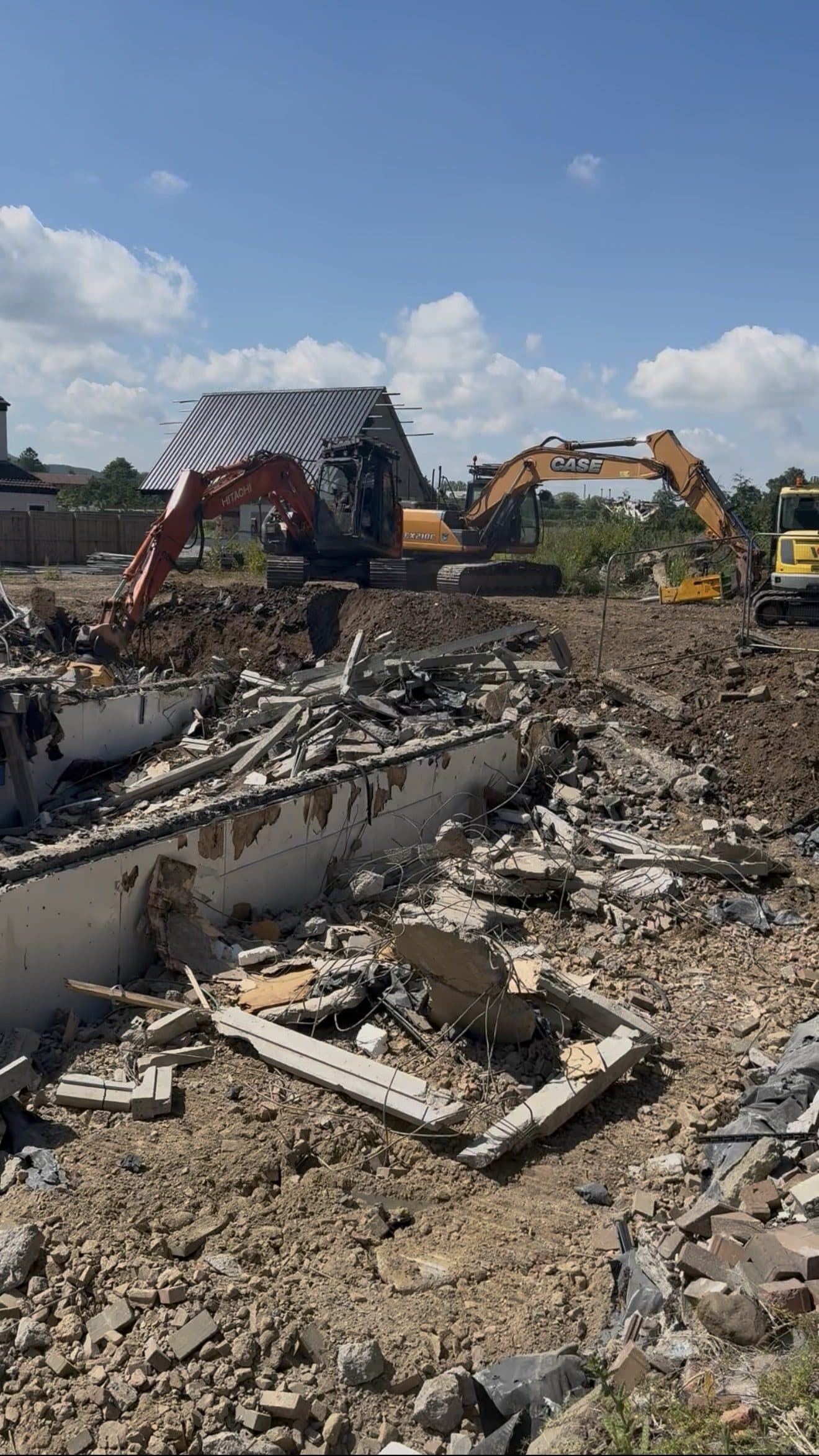 Excavators demolishing a building and clearing concrete rubble on a site at Stokesley