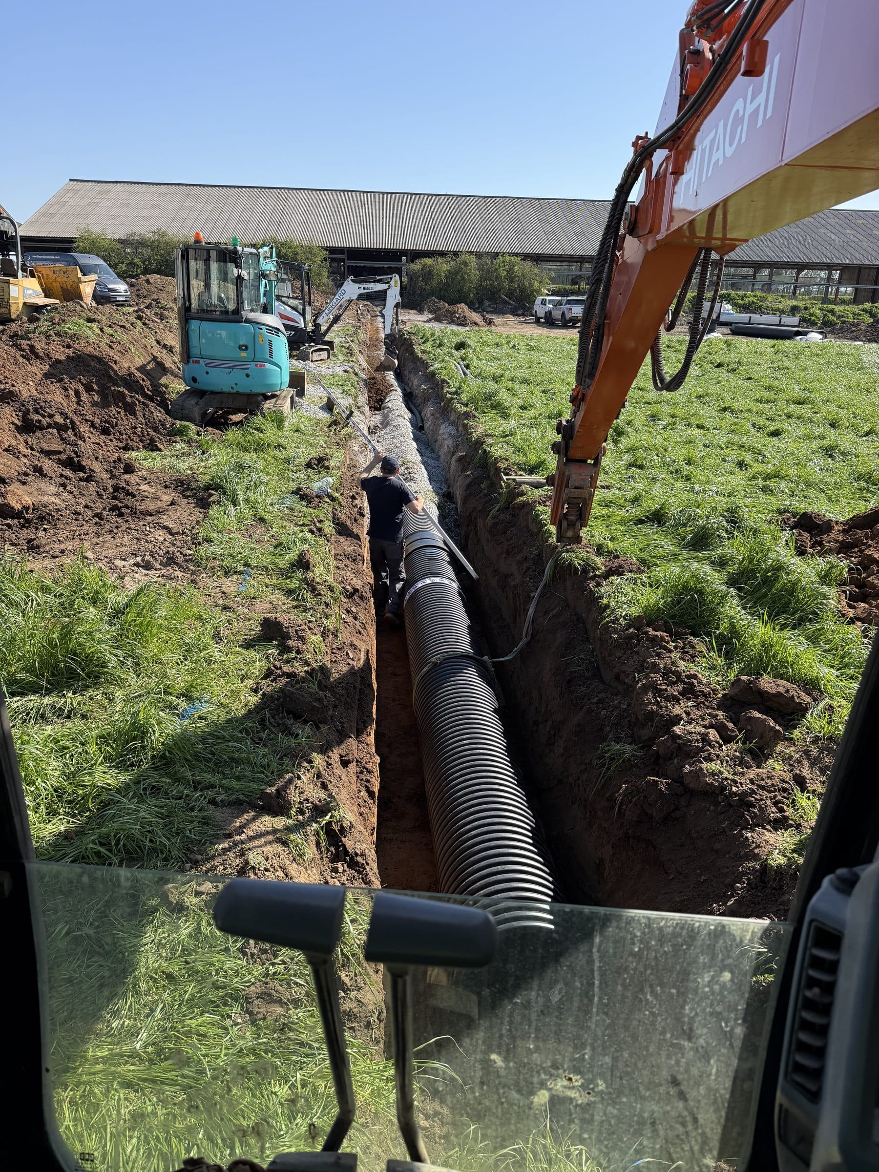 Large twinwall drainage pipe being laid in an open trench on farmland near Northallerton