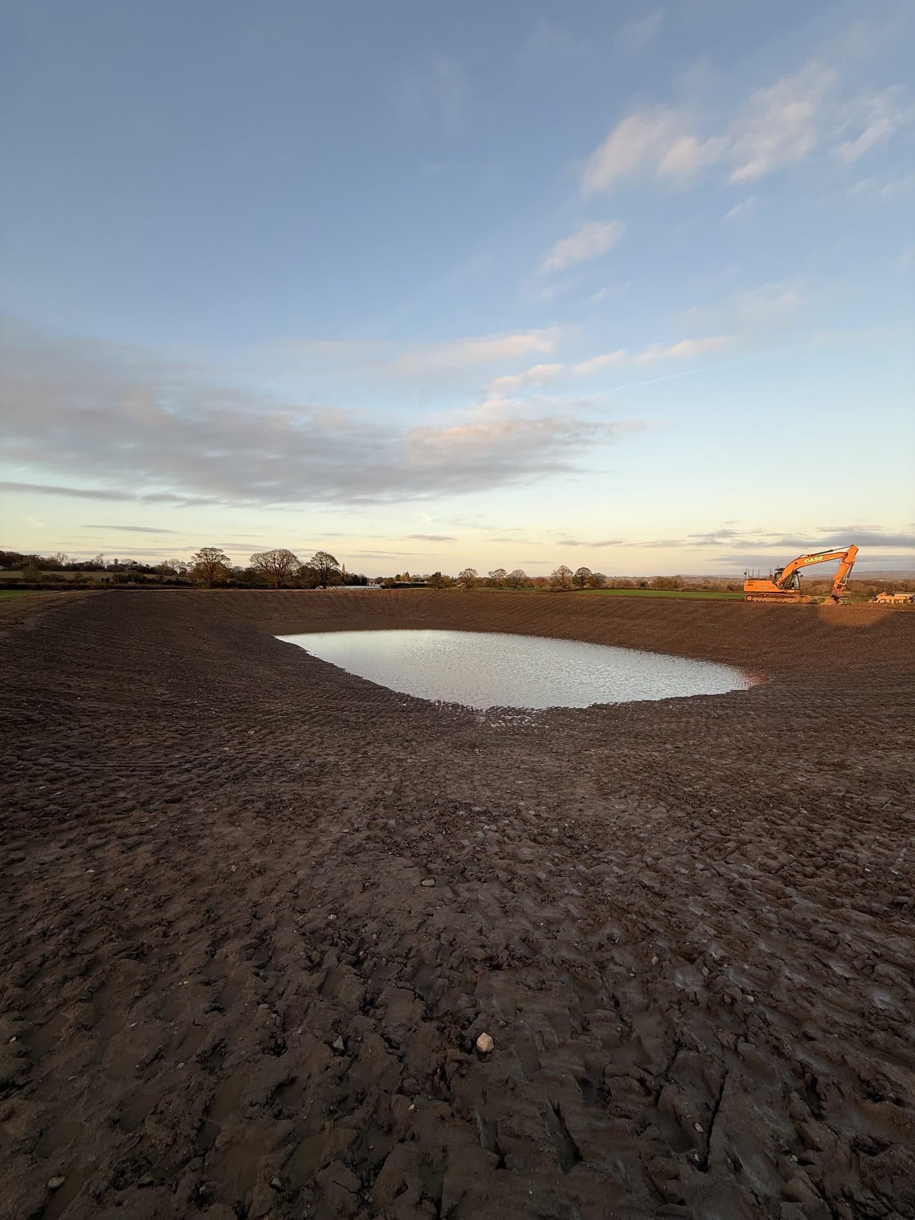 Completed earth-banked slurry lagoon at South Otterington with excavator on the bank