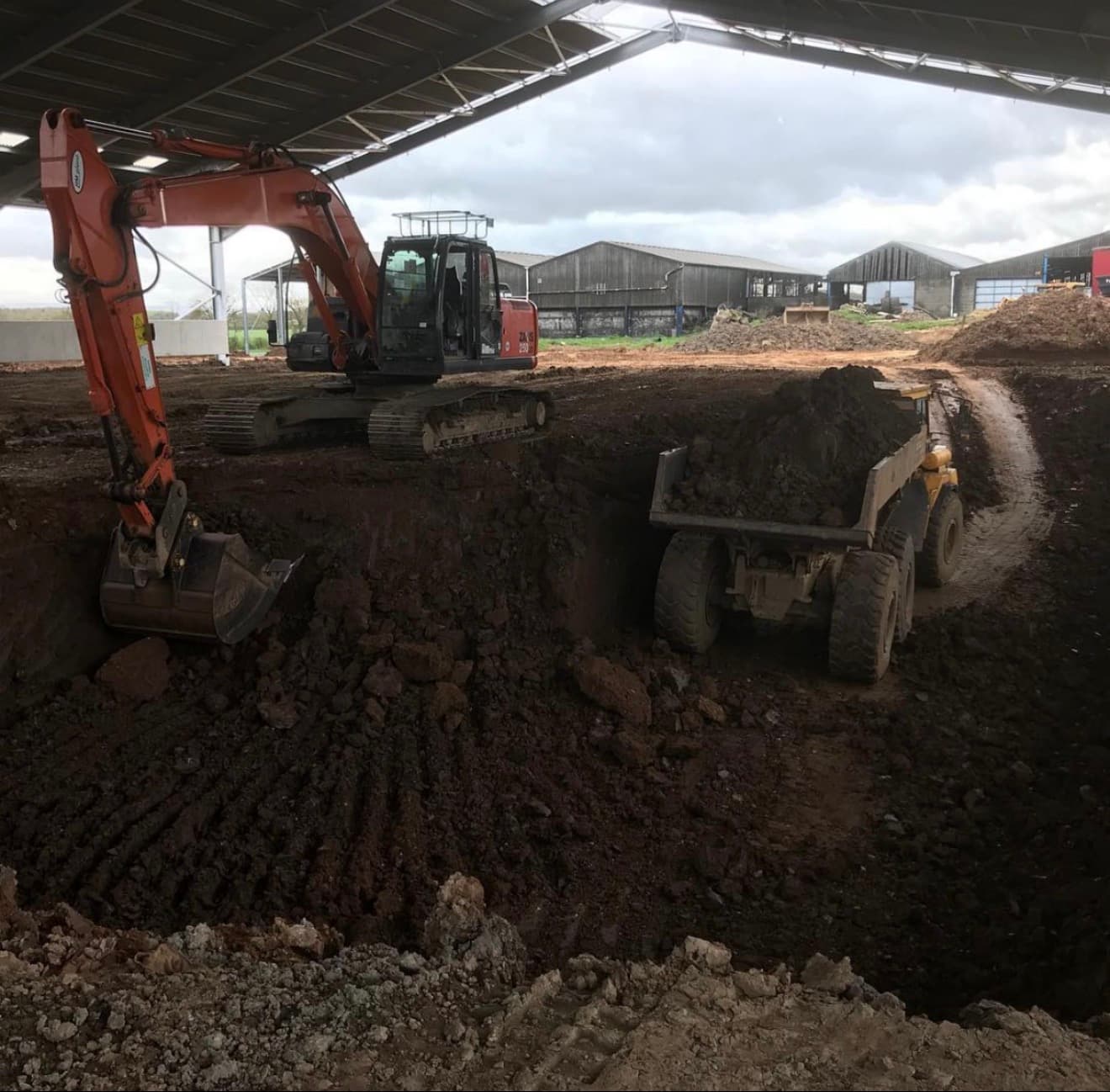 Heavy excavator and dump truck on a commercial groundworks site